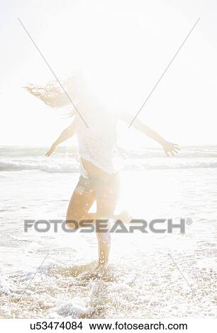 Picture - Woman standing on one leg in sea. Fotosearch