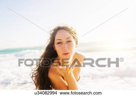 Picture - Woman throwing a kiss on beach. Fotosearch