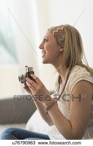 Stock Image - Woman using antique camera. Fotosearch