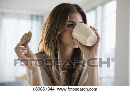 Picture - Woman with cookie and coffee. Fotosearch