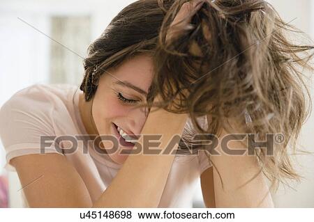 Stock Photo - Woman with hands in hair smiling. Fotosearch