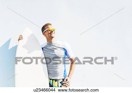 "Young surfer leaning against wall, looking up" View Large Photo Image Picture - "Young surfer leaning against wall, looking up". Fotosearch