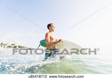 Stock Image - Young surfer running. Fotosearch