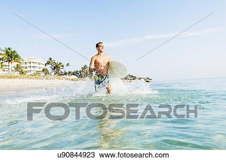 Stock Image - Young surfer running. Fotosearch