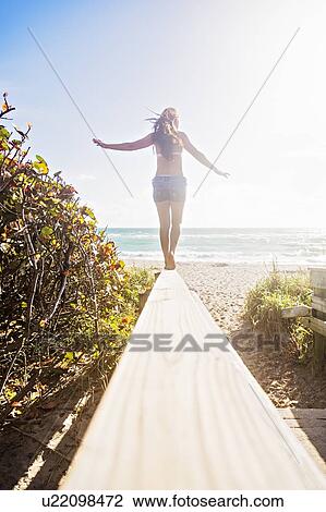 Young woman balancing on boardwalk View Large Photo Image Stock Image - Young woman balancing on boardwalk. Fotosearch