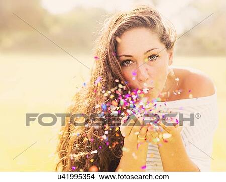 Picture - Young woman blowing confetti. Fotosearch