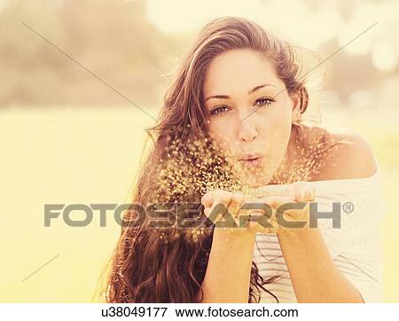 Stock Photo - Young woman blowing confetti. Fotosearch