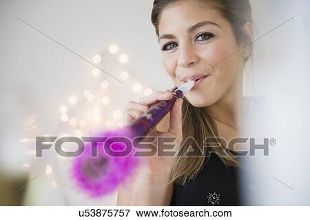 Young woman blowing noisemaker at party View Large Photo Image Stock Photo - Young woman blowing noisemaker at party. Fotosearch