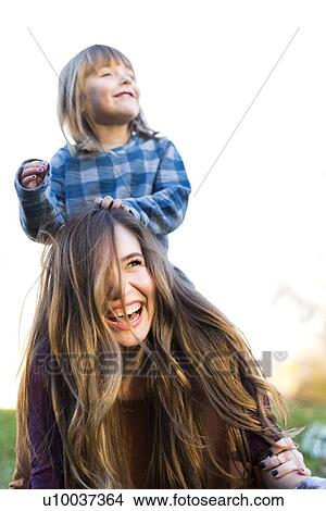 Young woman carrying girl (4-5) on shoulders View Large Photo Image Picture - Young woman carrying girl (4-5) on shoulders. Fotosearch