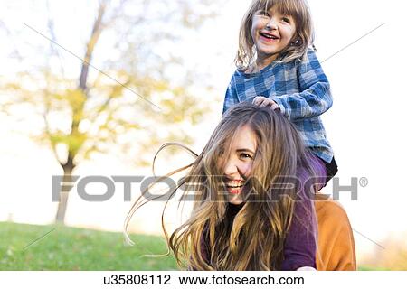 Young woman carrying girl (4-5) on shoulders View Large Photo Image Stock Image - Young woman carrying girl (4-5) on shoulders. Fotosearch