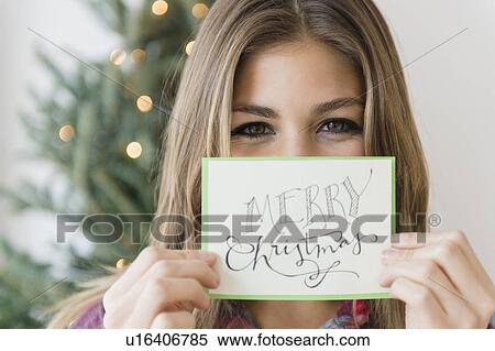 Stock Photography - Young woman holding greeting card for christmas. Fotosearch