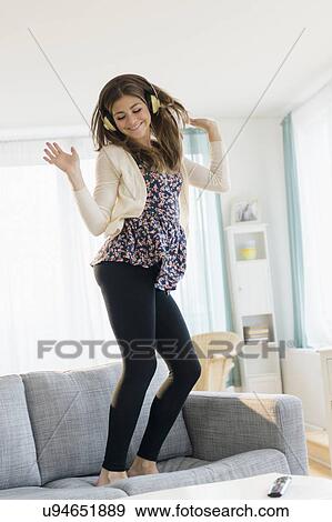 Young woman listening music and dancing on sofa View Large Photo Image Stock Photo - Young woman listening music and dancing on sofa. Fotosearch