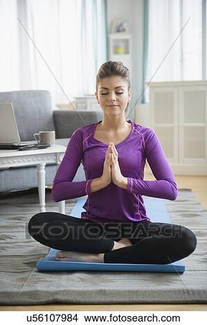 Young woman practicing yoga in living room View Large Photo Image Picture - Young woman practicing yoga in living room. Fotosearch