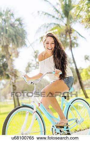 Young woman riding bicycle in park View Large Photo Image Stock Photography - Young woman riding bicycle in park. Fotosearch
