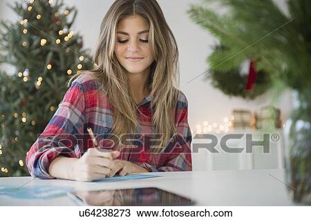 Young woman sitting at table and writing View Large Photo Image Stock Image - Young woman sitting at table and writing. Fotosearch