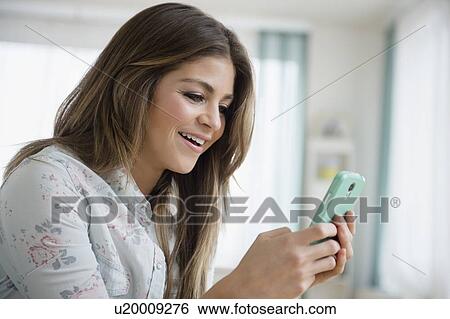 Stock Photograph - Young woman texting on mobile phone. Fotosearch