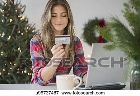 Stock Photo - Young woman using credit card during online shopping. Fotosearch