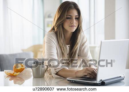 Young woman using laptop in living room View Large Photo Image Stock Photo - Young woman using laptop in living room. Fotosearch