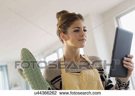 Young woman wearing cooking glove holding digital tablet View Large Photo Image Stock Image - Young woman wearing cooking glove holding digital tablet. Fotosearch