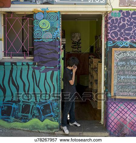 Stock Photo - "Boy talking on phone at doorway of a store, Valparaiso, Chile". Fotosearch