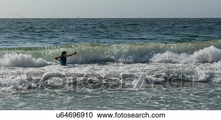 Stock Image - "Girl playing in ocean waves, Vina Del Mar, Chile". Fotosearch