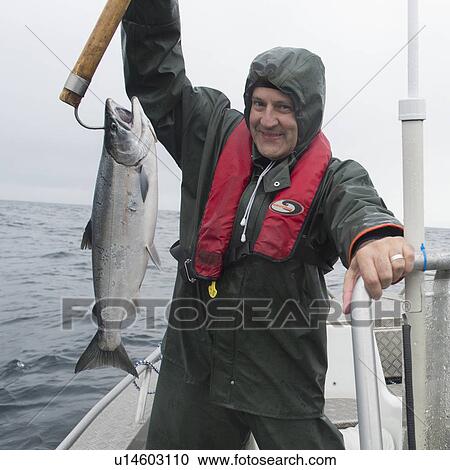Stock Image - "Man holding salmon fish, Skeena-Queen Charlotte Regional District, Hippa Island, Haida Gwaii, Graham Island, British Columbia, Canada". Fotosearch