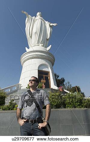 Stock Photo - "Man standing in front of the statue of Virgin Mary in San Cristobal Hill, Santiago, Santiago Metropolitan Region, Chile". Fotosearch