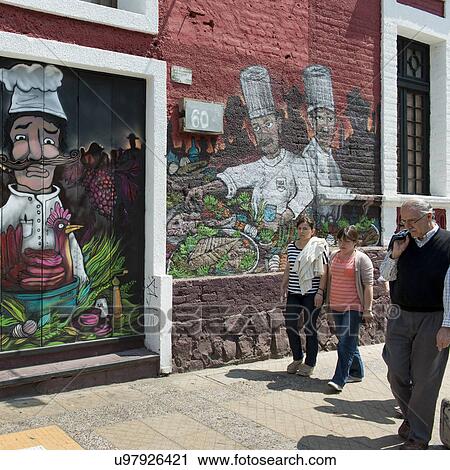 Stock Image - "People walking in front of murals on a restaurant wall, Santiago, Santiago Metropolitan Region, Chile". Fotosearch