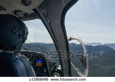 Stock Photograph - "Pilot flying Sikorsky helicopter, Skeena-Queen Charlotte Regional District, Haida Gwaii, Graham Island, British Columbia, Canada". Fotosearch