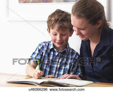 Stock Photograph - A six year old being helped with his homework by his mother at home. Fotosearch