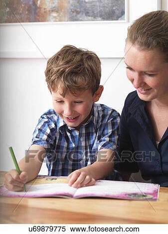 A six year old being helped with his homework by his mother at home View Large Photo Image Stock Photography - A six year old being helped with his homework by his mother at home. Fotosearch
