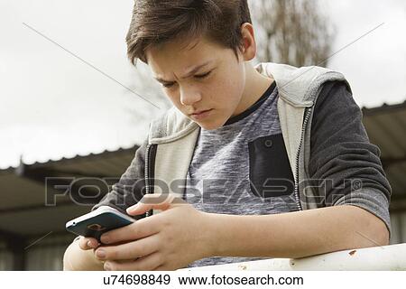 Anxious teenage boy reading smartphone text message View Large Photo Image Stock Photo - Anxious teenage boy reading smartphone text message. Fotosearch