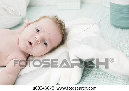 Baby lying down on bed View Large Photo Image Stock Photo - Baby lying down on bed. Fotosearch
