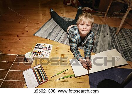 Boy lying on floor with watercolor paints and sketch pad View Large Photo Image Stock Photo - Boy lying on floor with watercolor paints and sketch pad. Fotosearch
