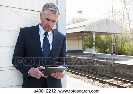 Businessman using digital tablet on railway platform View Large Photo Image Stock Image - Businessman using digital tablet on railway platform. Fotosearch