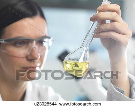Picture - Chemist looking at solution in flask during research experiment. Fotosearch