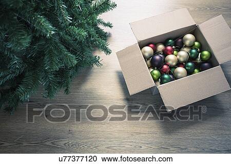 Stock Image - "Christmas baubles in cardboard box on floor, high angle". Fotosearch