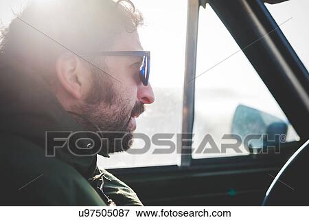 Close up of mid adult man wearing sunglasses in sunlit car View Large Photo Image Stock Photo - Close up of mid adult man wearing sunglasses in sunlit car. Fotosearch