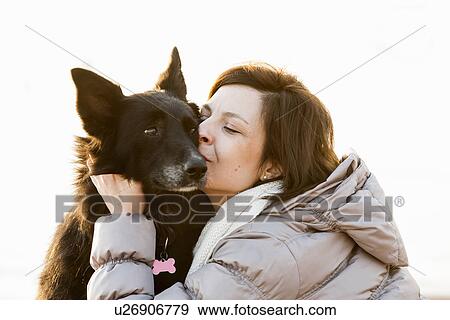 Stock Photo - Close up of mid adult woman kissing her dog. Fotosearch