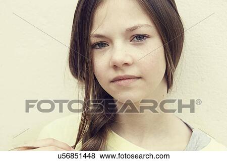Stock Photo - Close up portrait of girl with plaited hair in front of wall. Fotosearch
