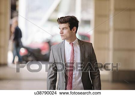 Confident young city businessman walking on sidewalk View Large Photo Image Picture - Confident young city businessman walking on sidewalk. Fotosearch