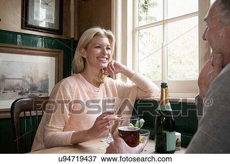 Stock Photo - Couple drinking and talking in pub. Fotosearch
