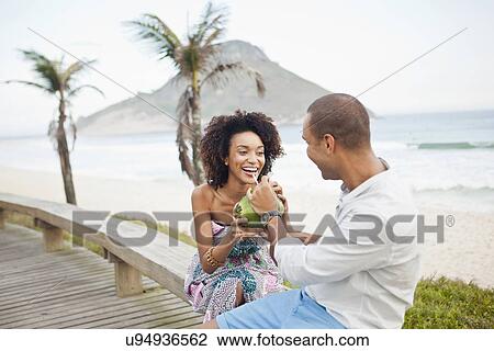 "Couple drinking coconut milk on boardwalk, Rio De Janeiro, Brazil" View Large Photo Image Stock Image - "Couple drinking coconut milk on boardwalk, Rio De Janeiro, Brazil". Fotosearch