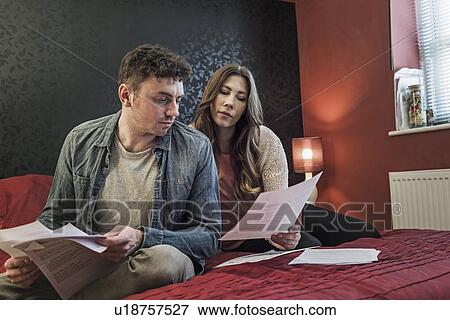 Couple on bed looking at paperwork View Large Photo Image Stock Photo - Couple on bed looking at paperwork. Fotosearch