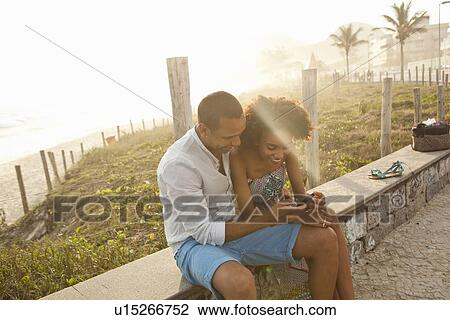 "Couple reading smartphone texts at beach, Rio De Janeiro, Brazil" View Large Photo Image Stock Image - "Couple reading smartphone texts at beach, Rio De Janeiro, Brazil". Fotosearch
