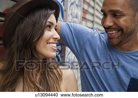 Stock Image - "Couple standing together, face to face, smiling, close-up". Fotosearch