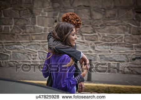 Stock Photo - "Couple walking along street, arms around each other". Fotosearch