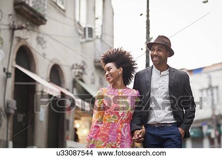 "Couple walking along street, hand in hand" View Large Photo Image Picture - "Couple walking along street, hand in hand". Fotosearch