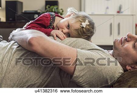 Stock Photograph - Daughter lying on fathers chest. Fotosearch