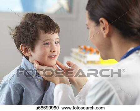 Stock Image - Doctor checking glands of young boy in clinic. Fotosearch